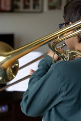 Fototapeta na wymiar Menino a tocar trombone em casa.