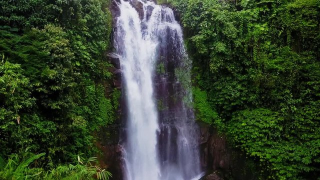 aerial shot with dron flying above beautiful Bali paradise waterfall and jungle rainforest in Asia travel destination and Summer vacations trip concept