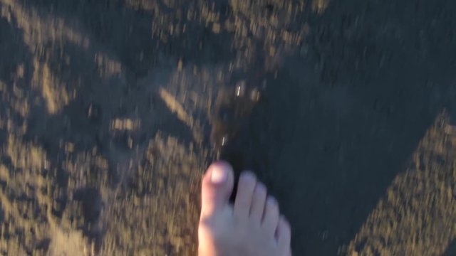Slow motion of bare feet coming out of water to the ground and walking on dirt soil