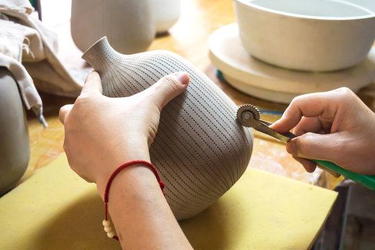 Potter's hands make a decorative pattern on vase