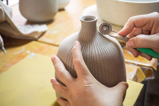Potter's hands make a decorative pattern on vase