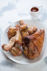 Roasted turkey leg and chicken drumsticks served on a white plate, selective focus, studio shot
