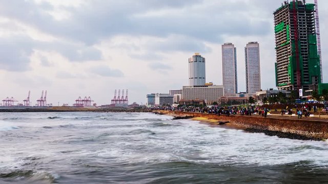 Colombo, Sri Lanka. Cityscape of Colombo, Sri Lanka with modern buildings at sunset. Ocean waves at night and cloudy sky. People at promenade area. Time-lapse at sunset, zoom in