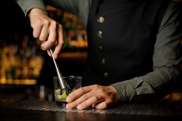 Fototapeta na wymiar Barman mixing a cane sugar with lime in the glass