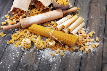 Various mix of pasta on grey rustic background. Diet and food concept.