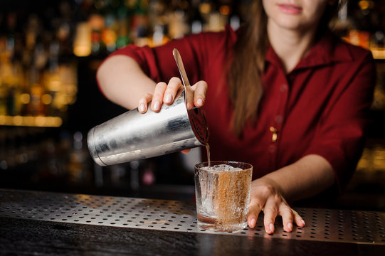 Female bartender filling cocktail into the glass