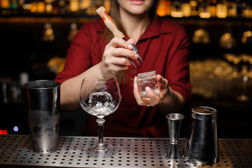 Bartender girl breaking ice cube for a cocktail