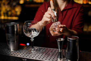 Bartender girl breaking an ice cube for the cocktail