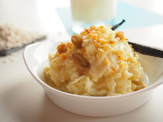 Creamy vanilla rice pudding with rice and milk on white and blue background