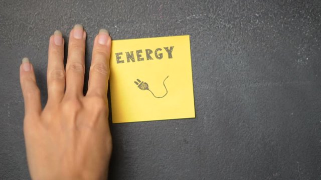 Closeup woman's hand sticking note with Energy word on the blackboard - video in slow motion
