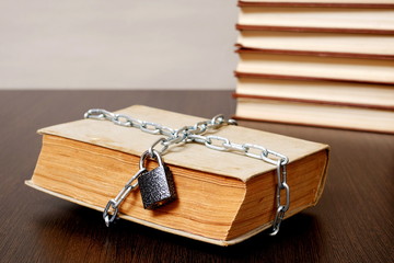 old book wrapped with chain and locked on padlock on table