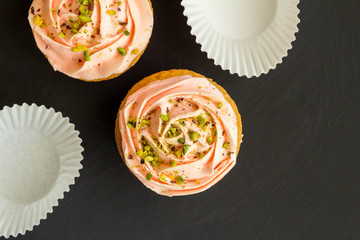 Two pink cup cakes close up on black background - Top view photo with space for text