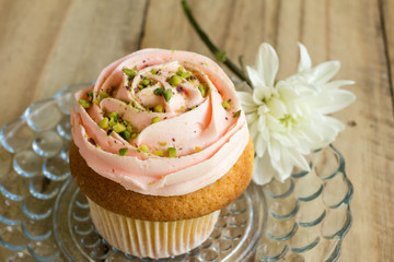 Obraz na płótnie Canvas Pink cup cake with white chrysanthemum flower on rustic wooden table