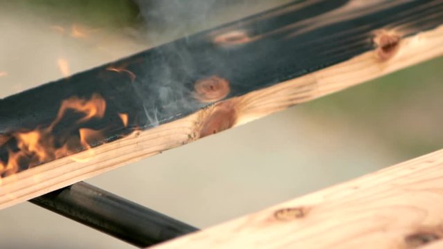 carpenter burns boards with a gas burner for blackening