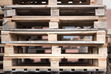 Stacks of old wooden pallets in an industrial yard.