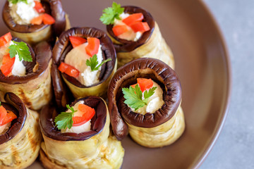 Rolls of grilled eggplant stuffed with cheese decorated by red paprika and parsley.