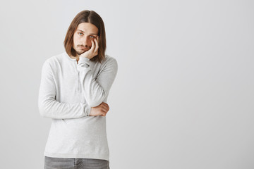 How long should I listen this boring talk. Portrait of bothered and annoyed attractive guy, leaning on palm and staring at camera with indifference, feeling boredom and tiredness, wanting to sleep