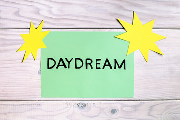 Word daydream with sun shapes on wooden table.