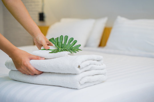 Hands of hotel maid putting leaves on the stack of towels