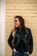 Portrait of a beautiful girl standing in front of a yellow brick wall. Looking away.