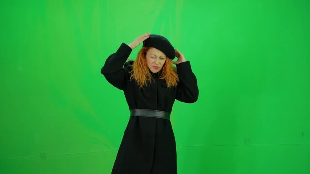 Young red hair elegant woman in black coat and beret trying hide from rain at green-screen 50fps