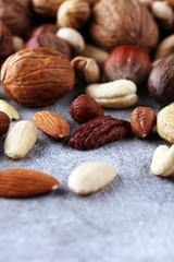mixed nuts on grey background. Healthy food and snack. Walnut, pecan, almonds, hazelnuts and cashews.
