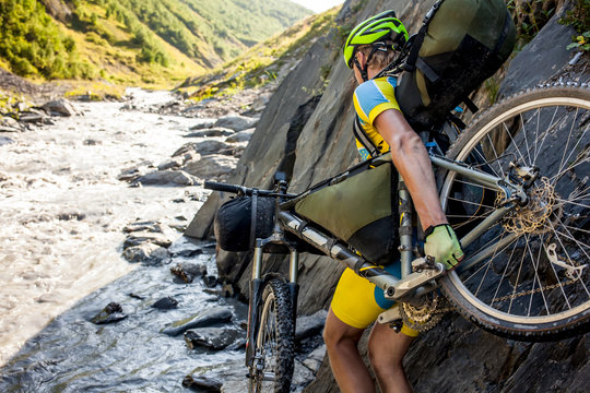 Mountain biker is crossing the river in the highlands of Tusheti region, Georgia