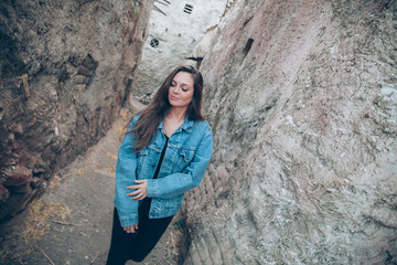 Portrait of an attractive young woman posing close to vintage village. Lifestyle and fashion concept