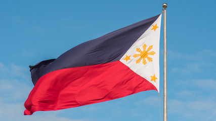 Flying bicolor flag of the Philippines with central golden sun representing the provinces and stars the islands.