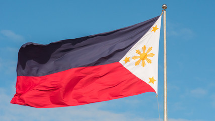 Flying bicolor flag of the Philippines with central golden sun representing the provinces and stars the islands.