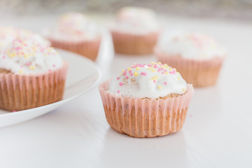 Muffins, cakes with confectionery on a white plate