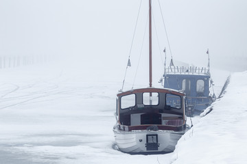 winter image of two small boats in the harbor with ice on the water