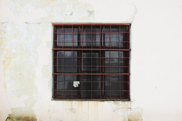 beige wall with a square window behind a thick rusty old grate for background