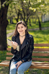 Beautiful caucasian girl student sitting on bench in park reading book