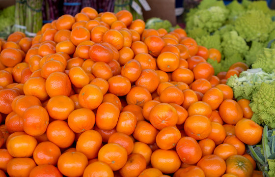 Tangerine citrus in the farmers market surrounded with vegetables background or backdrop