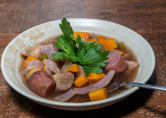 Crockpot stew in tan bowl on wooden table with spoon 