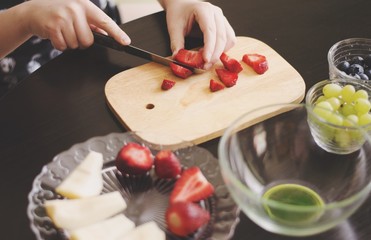 Kid is preparing a fruit salad