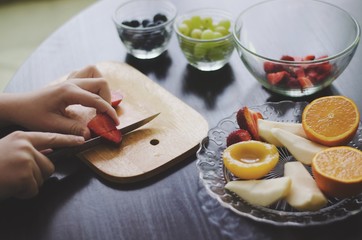 Kid is preparing a fruit salad 