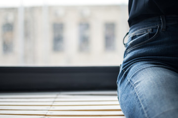 man in blue jeans sitting on the windowsill