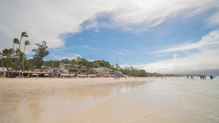 Tourists relaxing on the paradise shore of the White Beach in Boracay, Philippines