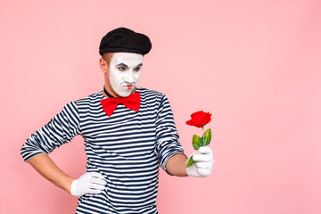 Comedian man holding red rose and looking seriously