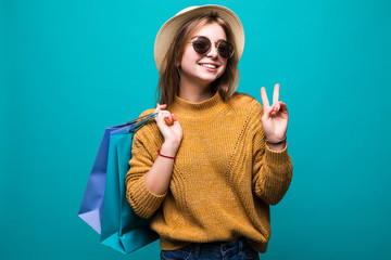 Fototapeta premium Beautiful happy woman holding shopping bags with victory gesture isolated on green background