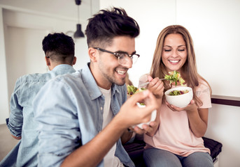 Young couple eating salad in a living room