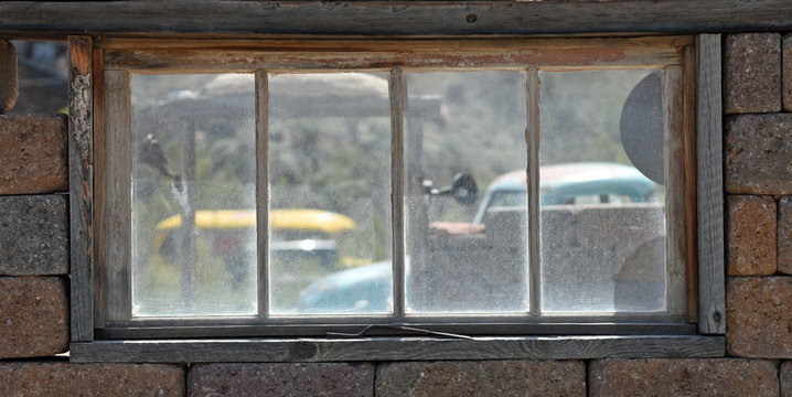 View through an old window to vintage cars
