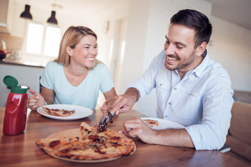 Couple eat pizza in kitchen
