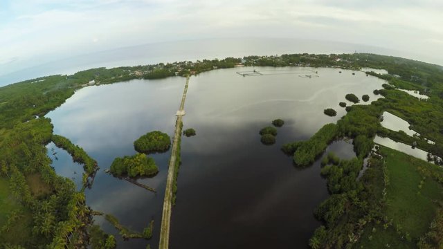 Filipino village with a lake. Anda. Bohol Island. Evening time. Aerial view. Fine artificial road.