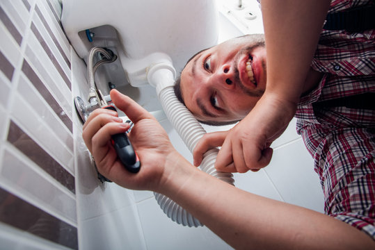 Plumber fixing a sink in bathroom with wrench