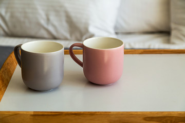 Close up grey and pink cups on breakfast tray in bedroom