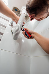 Plumber fixing a sink in bathroom with wrench
