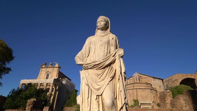 Statue of a woman with  the Roman Forum ruins in background in Rome, Italy